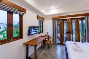 Phang Nga Origin Hotel في فانجنجا: غرفة نوم مع مكتب وسرير ونوافذ