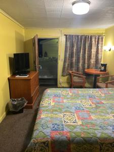 1 dormitorio con 1 cama, TV y mesa en Budget Inn Motel Chemult en Chemult