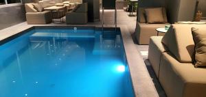 a blue swimming pool in a room with furniture at Boutique Hotel Acacia in Lovran