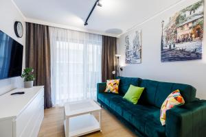 a living room with a green couch and a tv at Balticus Apartamenty Standard Promenada Gwiazd 14 in Międzyzdroje