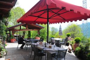 mężczyzna siedzący przy stole pod czerwonym parasolem w obiekcie Agriturismo La Fonte Di Mariella w mieście Gravedona