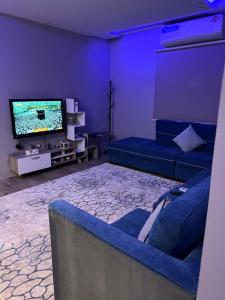 uma sala de estar com um sofá e uma televisão de ecrã plano em شقة نصف القمر em Meca