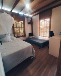 1 dormitorio con 2 camas y 2 ventanas en Espectacular Casa-Bonobo house al lado del rio en Acacías