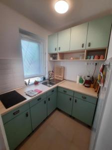 a small kitchen with green cabinets and a window at Füge Vendégház Csopak in Csopak +23 photos