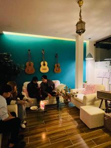 a group of people sitting in a living room with guitars on the wall at Cuti House in Da Lat