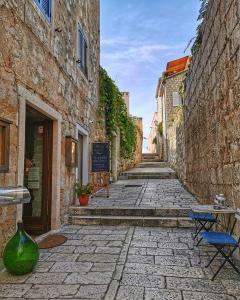 an alley in an old town with a table and chairs at Apartman Mira i Denis in Rab