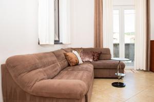 a brown couch sitting in a living room at Apartman Mira i Denis in Rab