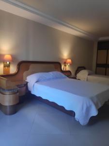 a hotel room with two beds and two lamps at Tower Icaraí Hotel in Niterói