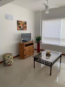 ein Wohnzimmer mit einem Couchtisch und einem Flachbild-TV in der Unterkunft Apartamento Capão da Canoa in Capão da Canoa