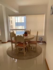 ein Esszimmer mit einem Tisch, Stühlen und einem Fenster in der Unterkunft Apartamento Capão da Canoa in Capão da Canoa