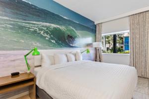 a bedroom with a bed and a large painting of the ocean at Postcard Inn On The Beach in St. Pete Beach
