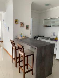 a kitchen with two chairs and a large counter top at Apartamento Capão da Canoa in Capão da Canoa