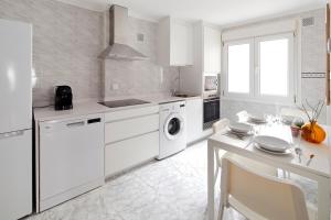 cocina blanca con electrodomésticos blancos y mesa en 165A Apto moderno 2 dormitorios en Gijón