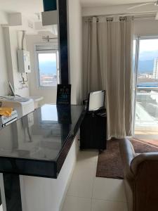 a living room with a glass counter with a television at Espaço Mahina - Unidade Dez - Apartamento para temporada Praia Grande Ocian in Praia Grande