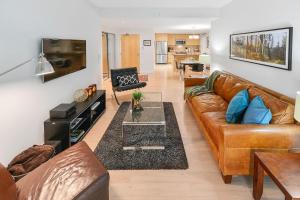 a living room with a brown leather couch and a table at Duet Executive Stay in Victoria