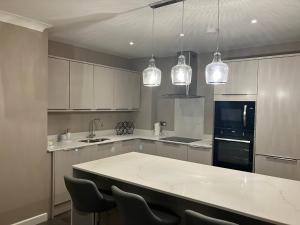 una cocina con armarios blancos y una gran encimera blanca en Buckingham Court en Saint Albans