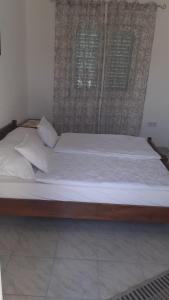 Cama grande de madera con sábanas y almohadas blancas en Apartments Zdenka, en Marina