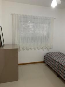 a bedroom with a window with a bed and a desk at Apartamento Capão da Canoa in Capão da Canoa