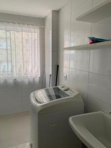 a white bathroom with a sink and a toilet at Apartamento Capão da Canoa in Capão da Canoa