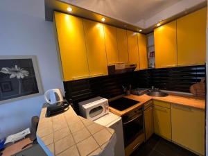 a kitchen with yellow cabinets and a microwave at Cute little apartment in Belgrade