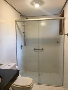 y baño con ducha de cristal y aseo. en Apto 3 Quartos Centro Gramado, en Gramado