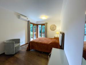 1 dormitorio con 1 cama, 1 silla y 1 ventana en Apto 3 Quartos Centro Gramado, en Gramado