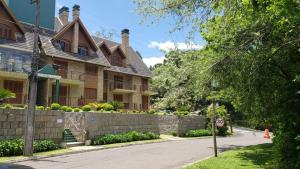 ein Haus mit einer Stützmauer vor einer Straße in der Unterkunft Apto 3 Quartos Centro Gramado in Gramado