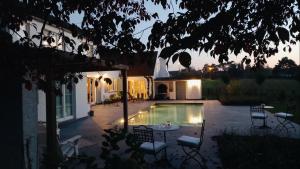 een achtertuin met een zwembad met stoelen en een tafel bij Chambres d'hôtes - Au Clos d'Amande in Lasne