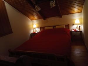 a bedroom with a red bed and two lamps on tables at Villa Gianna in Karpenisi