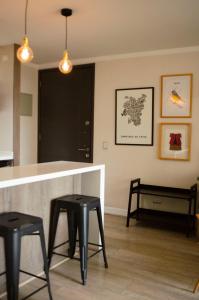 una cocina con 2 taburetes negros y una barra en Loica Suites, en Santiago