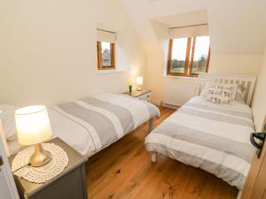 a bedroom with two beds and a table with a lamp at Granary Cottage in Southam