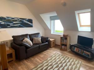 a living room with a couch and a tv at Quinag - luxury villa with sea views in Achiltibuie in Achiltibuie