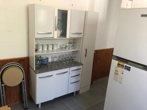eine Küche mit weißen Schränken und einem Kühlschrank in der Unterkunft Casa El Ceibo Reserva con Seña in Piriápolis