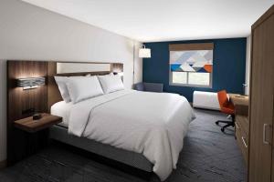 - une chambre avec un grand lit blanc et un bureau dans l'établissement Holiday Inn Express - Starke, an IHG Hotel, à Starke