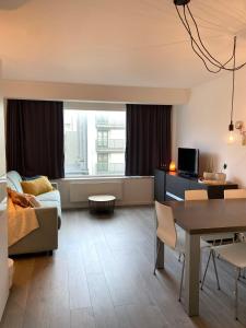 a living room with a couch and a table at Studio Delfien in Oostduinkerke +15 photos