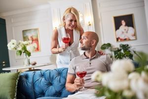 a woman holding up wine glasses to a man at The Doors Luxury Apartment in Mosonmagyaróvár