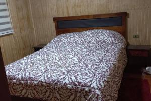 a bed with a brown and white comforter in a bedroom at Cabaña Mirador Del Cautín in Curacautín