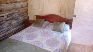 1 cama con cabecero de madera y almohadas en Cabaña Don Pepe, en Estancia Don Domingo en Curicó