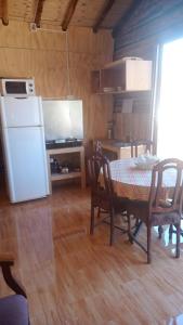Il comprend une cuisine équipée d'une table et d'un réfrigérateur blanc. dans l'établissement Cabaña Don Pepe, en Estancia Don Domingo, à Curicó