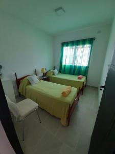 1 dormitorio con 2 camas, silla y ventana en CASA LA PAZ en Cafayate