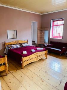 a bedroom with a large wooden bed and a couch at Travel Inn House Mestia • მოგზაურის სახლი in Mestia