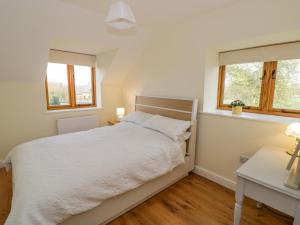een slaapkamer met een wit bed en 2 ramen bij The Granary in Southam