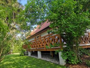 a house with a wooden deck in a yard at Bajkowy Domek Nad Samym Jeziorem in Narty