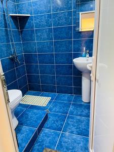 a blue tiled bathroom with a toilet and a sink at Travel Inn House Mestia • მოგზაურის სახლი in Mestia