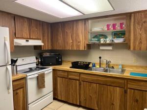 uma cozinha com armários de madeira e um frigorífico branco em Professor Rousseau's Tiki Hideaway em Crystal River