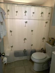 uma casa de banho com uma cortina de chuveiro com palmeiras em Professor Rousseau's Tiki Hideaway em Crystal River