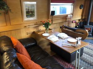 a dining room with a table and a leather couch at Willow - Cottage on the River, Luxury Houseboat in Little Baddow