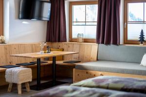 a room with a table and a bench and windows at Apartment LENA in Obertilliach