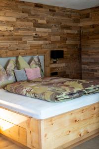 Cama en habitación con pared de madera en Apartment LENA, en Obertilliach