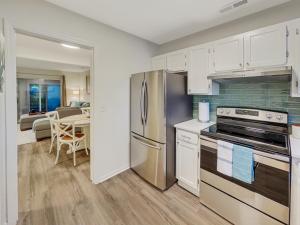 a kitchen with white cabinets and a stainless steel refrigerator at 5 Min to Beach—King Beds in Charleston